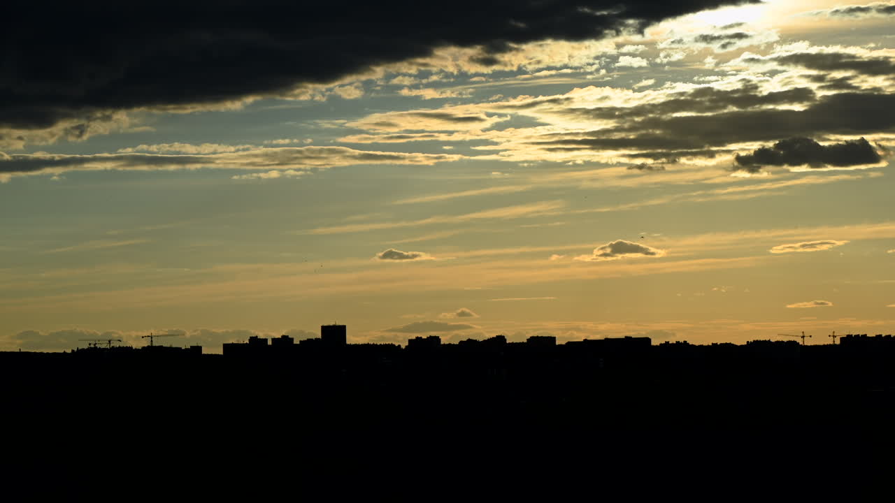 Time lapse de la silueta del skyline de una ciudad al atardecer con espectaculares nubes doradas