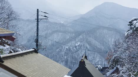 snow falling on roofs of yamadera temple in japan, slow pan shot in 4k