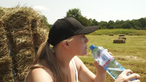 Girl-hiker-walks-through-rural-farm-field-strewn-with-harvested-hay-bales