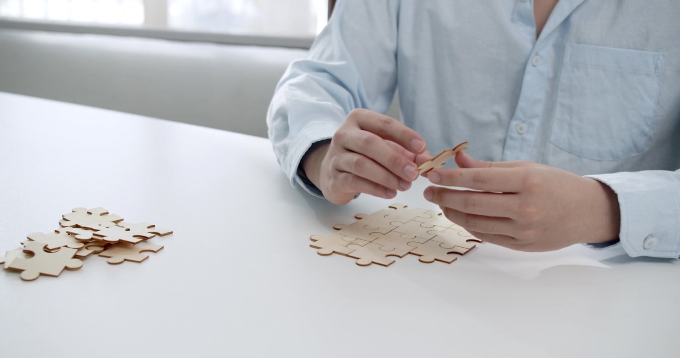 Giovane uomo che assembla un puzzle di legno, simboleggiando l'importanza della collaborazione e del networking per il successo aziendale.