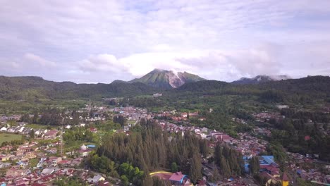 Forward elevating drone shot of active volcano Mount Sibayak flying above Berastagi town in North Sumatera Indonesia