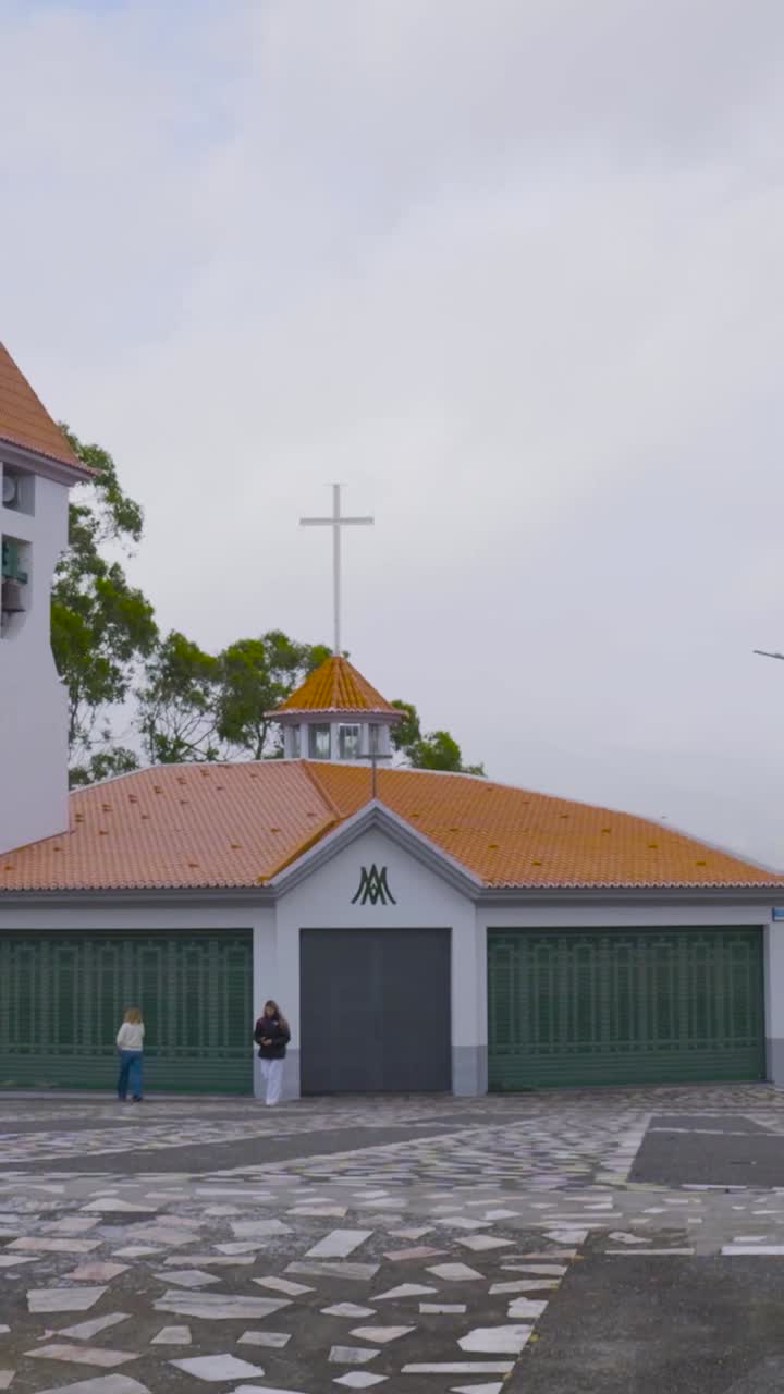 Due donne che camminano verso una chiesa con una croce