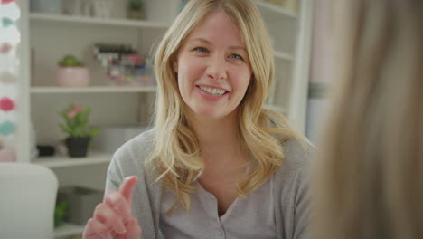 Over-the-shoulder-view-of-mother-talking-with-teenage-daughter-wearing-pyjamas-sitting-on-bed--in-bedroom---shot-in-slow-motion