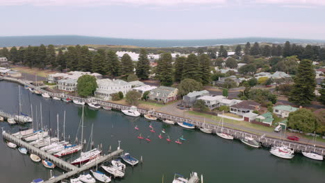 toma aérea de arriba hacia abajo de remeros de pie remando entre barcos en el puerto de port fairy, australia