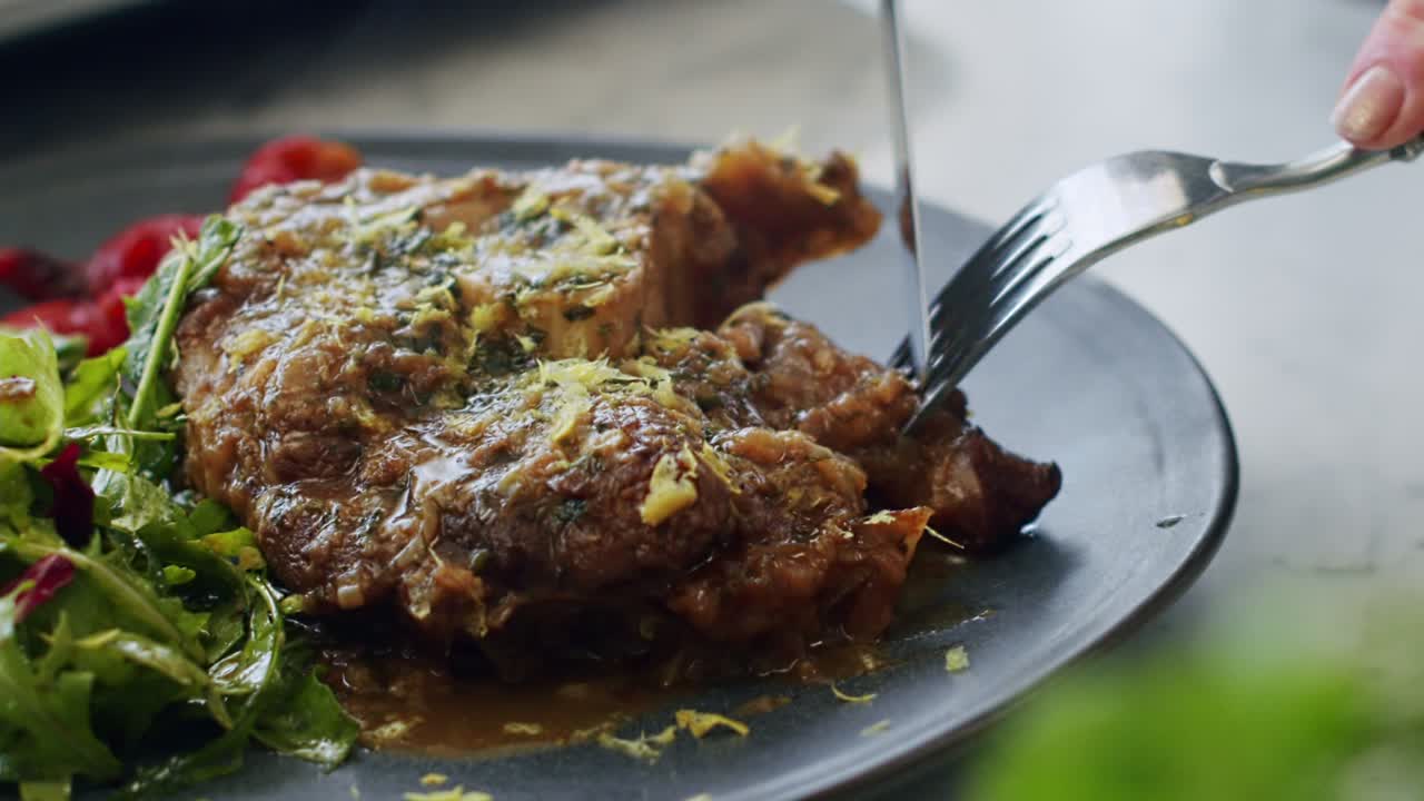 mujer cortando delicioso ossobuco guisado servido con ensalada y ketchup