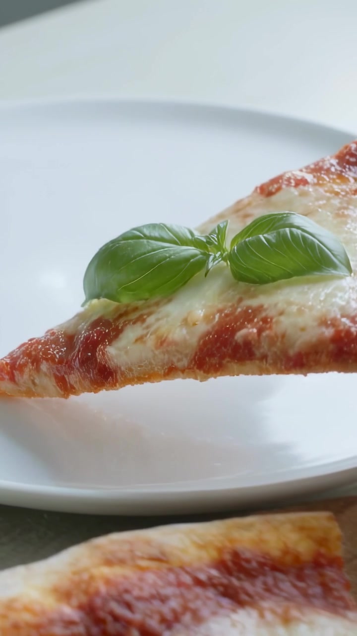 Video verticale: Sollevare una fetta di pizza margherita da un tagliere sul tavolo, facendola scivolare su un piatto bianco per servire.