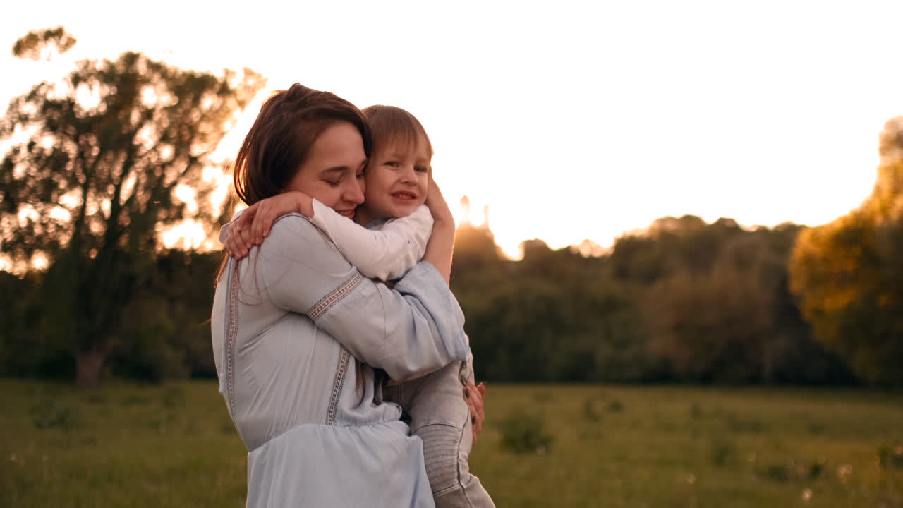 El hijo besa a su madre sentado al atardecer en un campo abrazando y ...