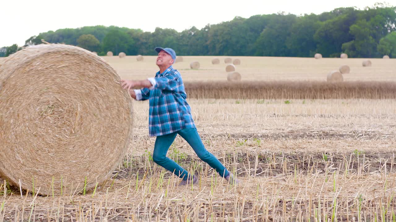 un granjero sonriente rodando balas de heno y gestando en la granja