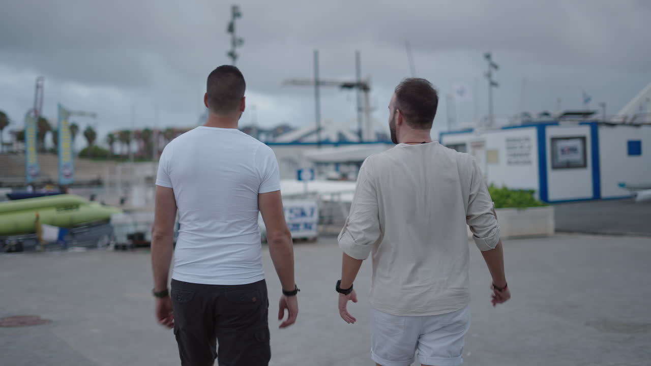 Two men walking through a marina