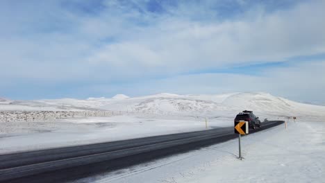 wide shot of  car driving on iceland road with snow white mountains and sunset countryside, winter time. 4k