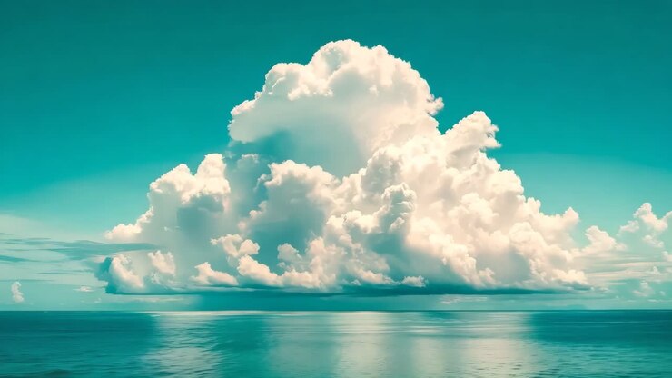 A large cloud over a body of water under a blue sky