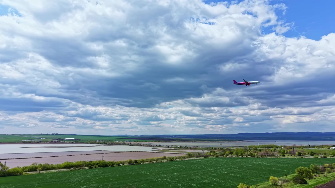 Vliegtuig dat overdag over een groen veld en rivier vliegt, met wolken in de lucht