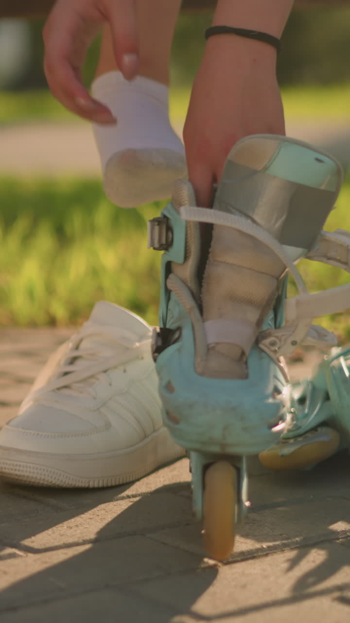 롤러 스케이트에 도달 한 개인의 부분적 인 시각, 스니커에서 오른쪽 다리를 제거 한 후 그것을 입을 준비, 발에  스니커와 잔디를 배경으로 빛을 부드럽게 는