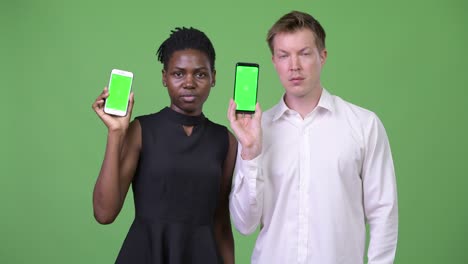 two young multi-ethnic business couple showing phone together