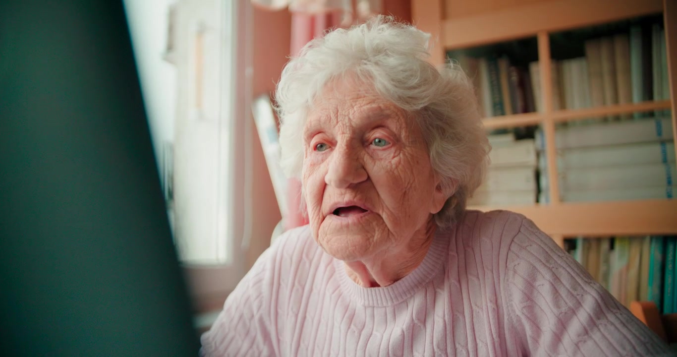 La nonna digita sulla tastiera del laptop e lavora al suo laptop