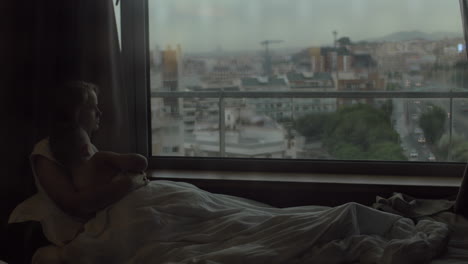 Mom-and-son-looking-at-evening-city-lying-in-bed