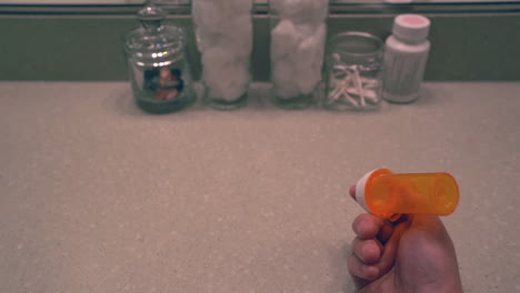 man opening a pill bottle and taking opioid at his bathroom vanity 2