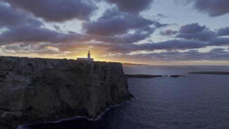 Acantilado-Paisaje-Costero-Sol-Brillando-Debajo-Del-Faro-Costero-De-Menorca-Drone-Aéreo-Panorámica-Cámara-Lenta