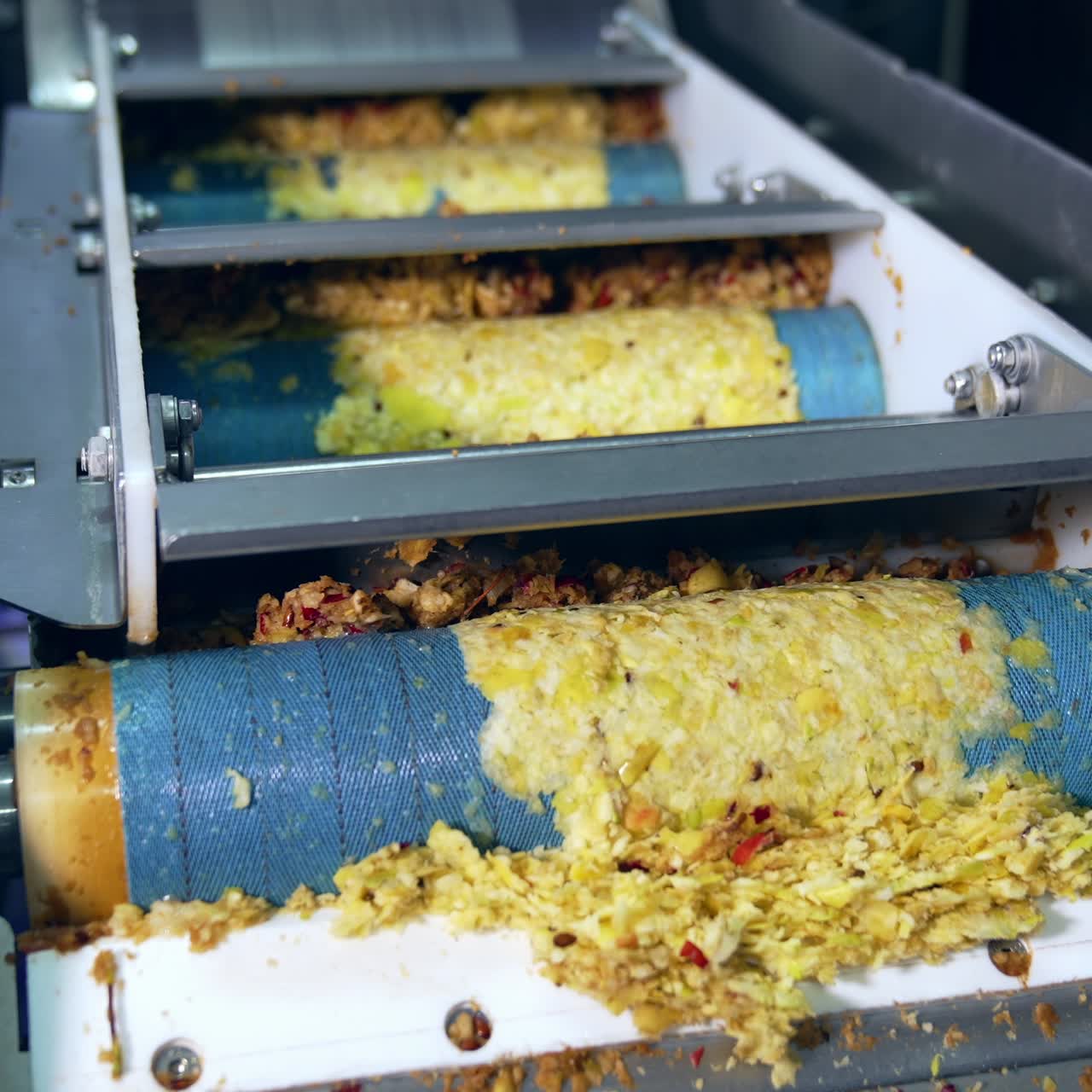 Rotating shafts transporting mashed apples pulp. Conveyor line at the factory producing organic apple juice fruit