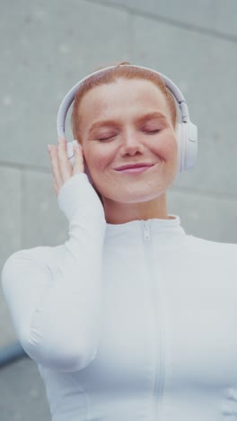 a joyful moment: a young woman enjoys music with wireless headphones, connecting with her playlist while savoring the melodies in modern urban environment