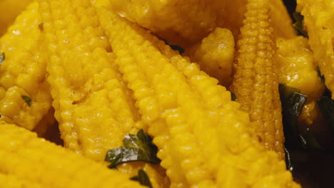 close-up of fermented yellow mini corn with black pepper on plate. preservation of vegetables in glass jars. fermentation preserved mini corns with spices macro.