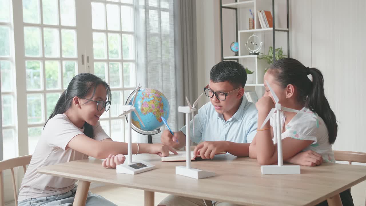 Asian Kids Study About Ecology Problems And Their Solution With Wind Turbine Model And Globe At School. Renewable Energy