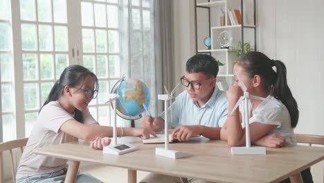 asian kids study about ecology problems and their solution with wind turbine model and globe at school. renewable energy