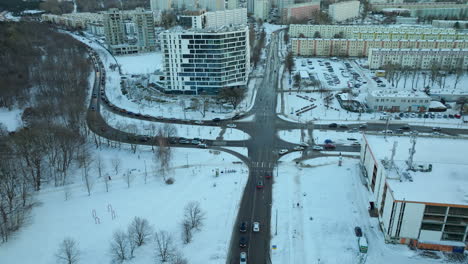 aerial view of a modern urban intersection surrounded by snow-covered trees and buildings, showcasing the organized chaos of city infrastructure against the quiet of winter in gdańsk