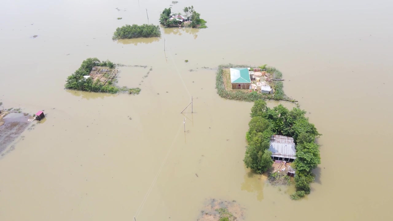 ภาพมุมสูงจากโดรนของหมู่บ้านชนบทที่ถูกน้ำท่วม โดยมีบ้านเรือนโดดเดี่ยวล้อมรอบด้วยน้ำท่วม แสดงถึงการเปลี่ยนแปลงสภาพภูมิอากาศและภัยธรรมชาติ