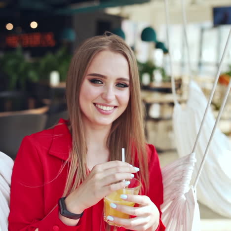 portrait of smiling young woman. beautiful model with perfect makeup sitting on a swing and looking on camera indoors.