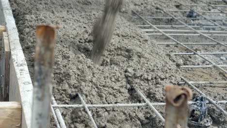 splattering wet cement poured over new concrete slab at building site