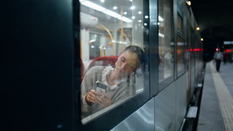 mujer usando un teléfono inteligente en un tren por la noche