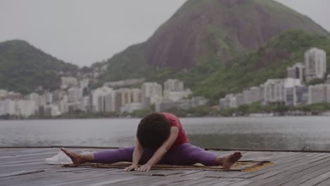 woman doing yoga on a pier overlooking a city and mountains