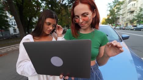 dos mujeres mirando una computadora portátil afuera