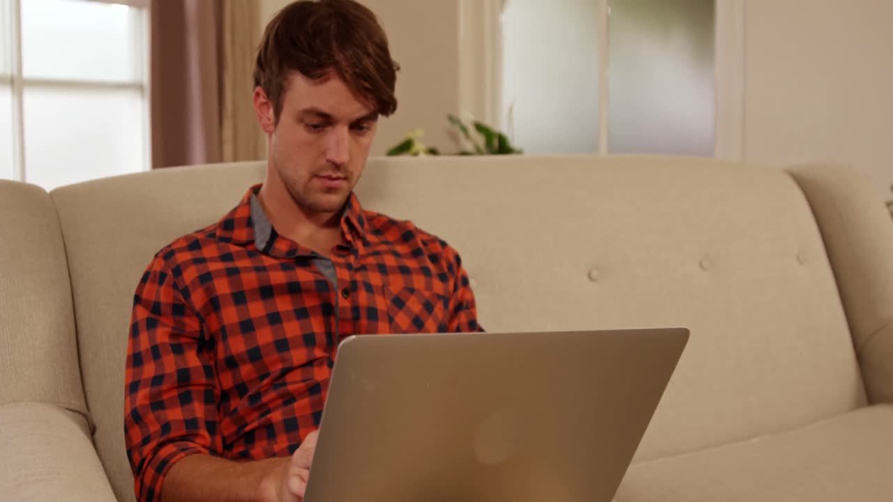 hombres jóvenes usando una computadora portátil sentados en el sofá