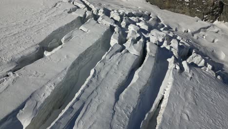 aerial-push-in:-snowy-plain-in-the-swiss-alps-and-crevasses,-Switzerland