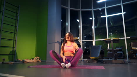 Slender brunette girl doing exercises in a pink sports suit.