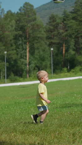 cute playful toddler boy runs along lush meadow and scratches side spending time in large sunny resort park on summer day slow motion