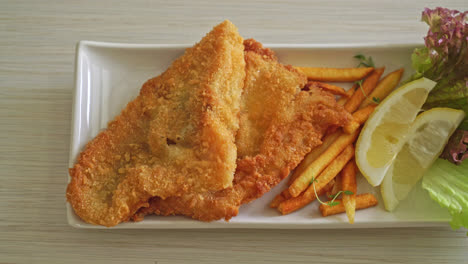 fish and chips - fried fish fillet with potatoes chips and lemon on white plate