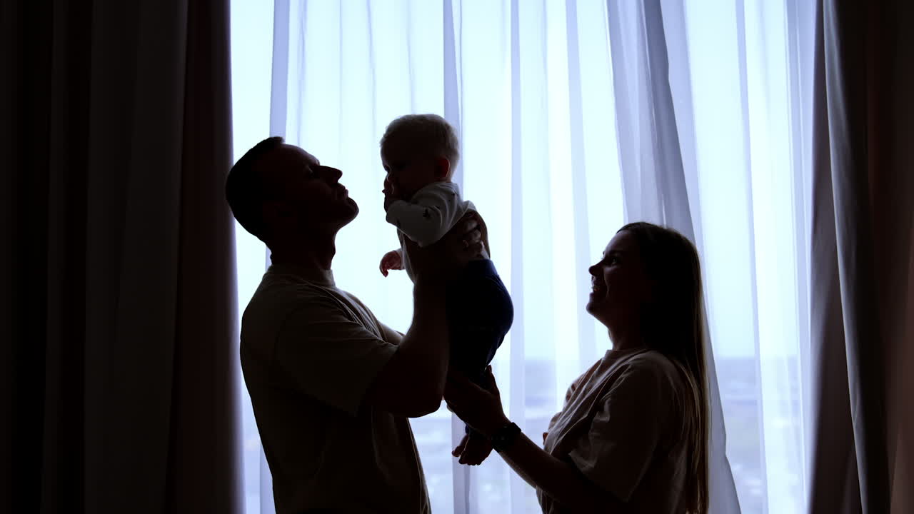 Playful parents with small baby. Happy family lifting cute boy.