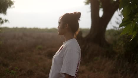 young woman in white t-shirt standing outdoors at golden hour