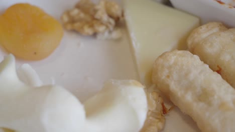 close-up of a cheese plate with dried apricots, walnuts, and a fork