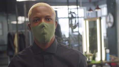 retrato de barbero afroamericano con máscara protectora en el trabajo