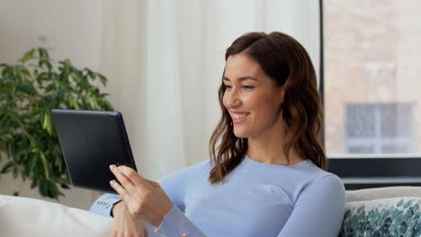 Concepto-De-Gente,-Tecnología-Y-Ocio.-Feliz-Joven-Afroamericana-Sentada-En-Un-Sofá-Con-Una-Computadora-Tablet-Haciendo-Una-Videollamada-Y-Saludando-Con-La-Mano-En-Casa