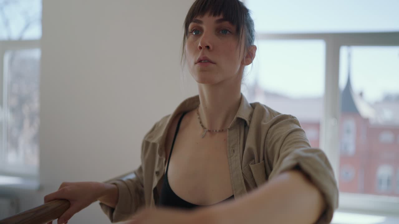 Ballet dancer stretching at the barre in a studio