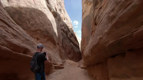 a camera moving through a slot canyon while passing a man taking a picture.  this is a 60fps slow motion clip.