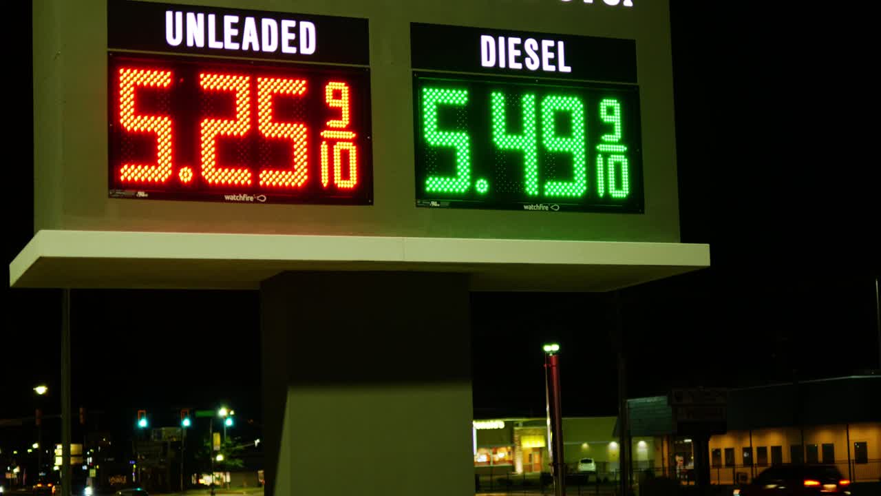 Gas station prices LED light up sign for regular and diesel fuel at night over 5 dollars per gallon credit and cash price, during 2021 2022 recession, ground up shot with angel zooming in on price