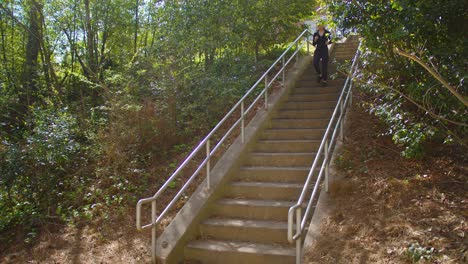 A-fit,-young-woman-descends-a-staircase-in-a-park-to-go-running