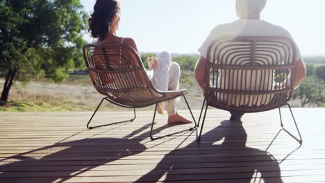 Senior-couple-with-arms-outstretched-while-sitting-in-chair-4k