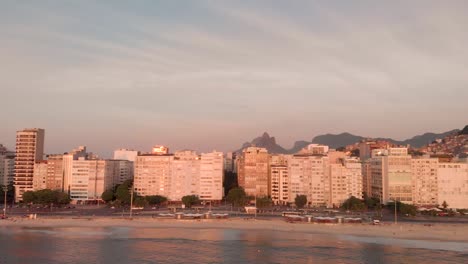 Panorama-Aéreo-Que-Muestra-El-Barrio-Total-De-La-Playa-De-Copacabana-En-Río-De-Janeiro-Con-Los-Edificios-De-Gran-Altura,-Las-Favelas,-La-Montaña-Del-Pan-De-Azúcar-Y-La-Plataforma-Petrolera-Al-Frente-En-La-Hora-Dorada-Del-Amanecer